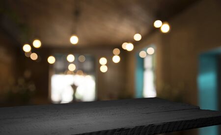 Empty wood table top on blur light gold bokeh of cafe restaurant in dark background.の写真素材