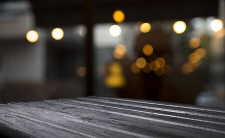 Empty wood table top on blur light gold bokeh of cafe restaurant in dark backgroundの写真素材