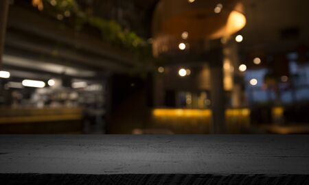 Empty wood table top on blur light gold bokeh of cafe restaurant in dark background.の写真素材