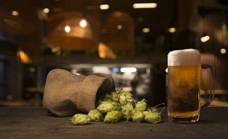 Beer brewing ingredients Hop in bag and wheat ears on wooden cracked old table. Beer brewery concept. Hop cones and wheat closeup. Sack of hops and sheaf of wheat on vintage background.の写真素材