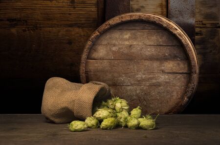 Oktoberfest beer barrel and beer glasses with wheat and hops on wooden table