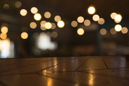 Image of wooden table in front of abstract blurred restaurant lights backgroundの写真素材