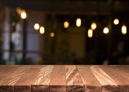 Empty brown wooden table and blur background of abstract of resturant lights people enjoy eating ,can be used for montage or display your productsの写真素材