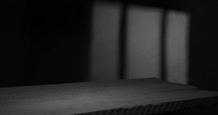 Old wood table with blurred concrete block wall in dark room background.の写真素材