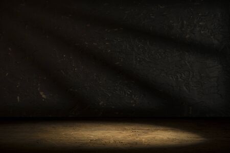 Old wood table with blurred concrete block wall in dark room background.