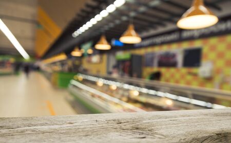Supermarket background, Counter over blur grocery background, Wooden desk, table, shelf and blur woman shopping at supermarket, Wood counter for grocery store retail product display backdrop, templateの写真素材