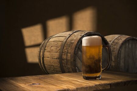Beer barrel with beer glasses on a wooden table. The dark brown background.
