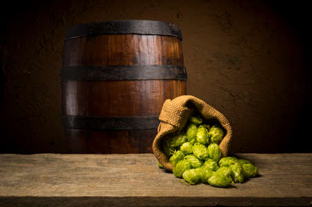 Beer. Still life with Vintage beer barrel and glass light beer. Fresh amber beer concept. Green hop...