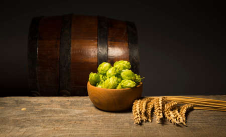 Beer. Still life with Vintage beer barrel and glass light beer. Fresh amber beer concept. Green hop...