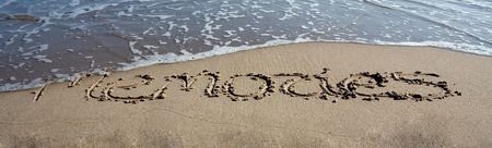 waves washing out the writing on the beachの写真素材