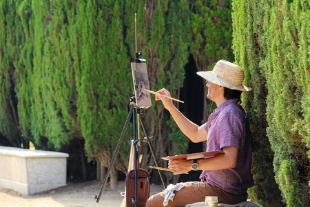Painter is sitting in Barcelona ciudadela park among green plantsのeditorial素材