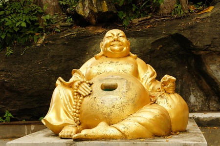 happy buddha in front of the cave temples in thailand.の写真素材
