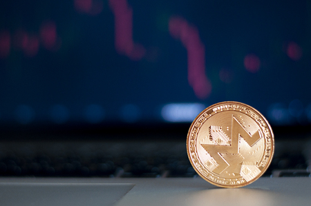 Golden Monero in front of laptop with stock exchange graph background. Digital money concept.の写真素材