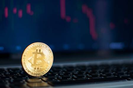 Bitcoin gold coin and defocused chart background. Virtual cryptocurrency concept.の写真素材