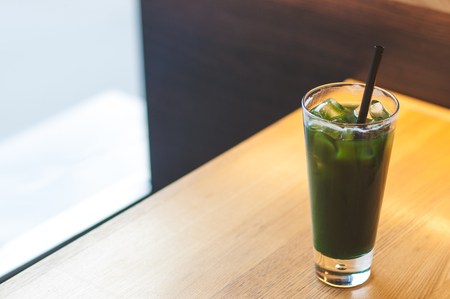 Ice coffee wich blue green cocktailcold coffee and green, blue syrup. Summer refreshing cocktail on wooden table in a coffee house, restaurant.の写真素材