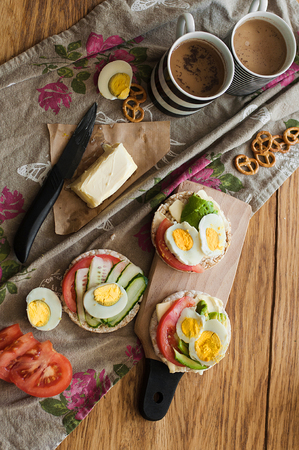 Toast with avocado, egg, tomatoes and cup of coffee. Healthy breakfast. Hands holding plate with healthy breakfast food. Concept of healthy lifestyleの写真素材