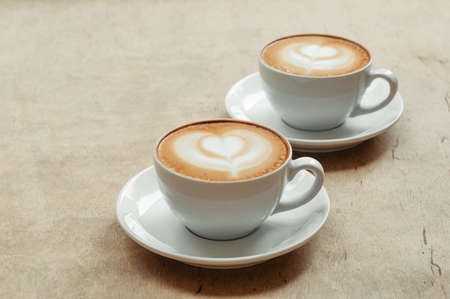Two cup of cappuccino with latte art on wooden background. Hot coffee on table. Top view, flat lay copy space for text. Beautiful foam, copy space.の写真素材