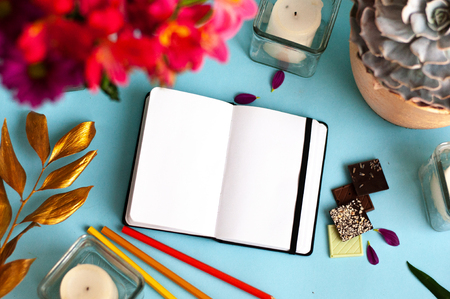 Styled mockup with blank notepad and pink flower, gold leaf, candle, pen on color background. Flat lay, top view, copy spaceの写真素材