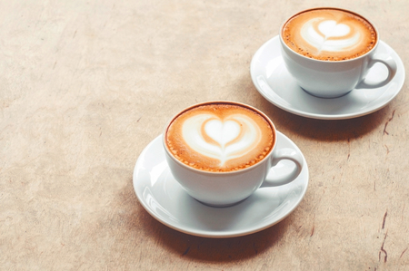 Two cup of cappuccino with latte art on wooden background. Hot coffee on table. Top view, flat lay copy space for text. Beautiful foam, copy space.の写真素材