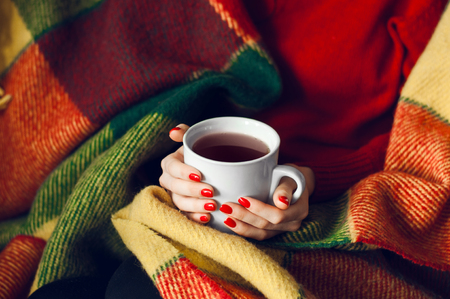 warm cup of hot coffee warming in the hands of a girlの写真素材