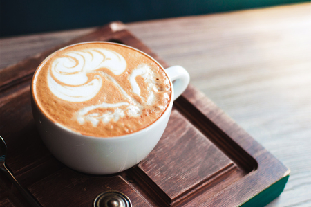 Top view of hot coffee cappuccino latte art in white ceramic cup on wooden plate. Coffee cup top view on old wooden. Coffee cup in coffee shopの写真素材