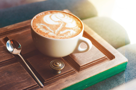 Top view of hot coffee cappuccino latte art in white ceramic cup on wooden plate. Coffee cup top view on old wooden. Coffee cup in coffee shopの写真素材