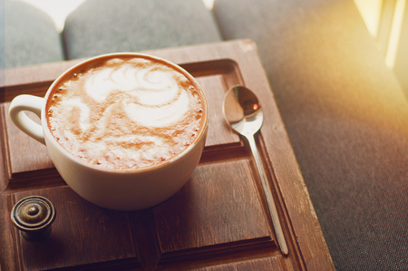 Top view of hot coffee cappuccino latte art in white ceramic cup on wooden plate. Coffee cup top view on old wooden. Coffee cup in coffee shopの写真素材