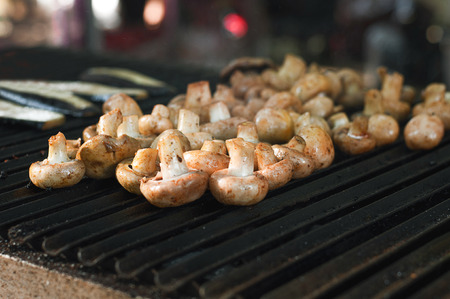 Champignon white, mushroom barbecue roasted on metal grill. Diet vegan bbq. Fungi kebab closeup at picnic outdoors, copy space on background of grill grateの写真素材