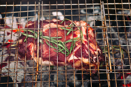 Grilling steaks on flaming fire with rosemaryの写真素材