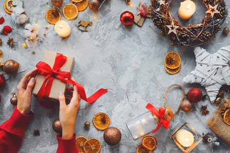Christmas background with decorations and female hands, gift box, candles, oranges, cardamom, balls. Flat lay. Copy spaceの写真素材