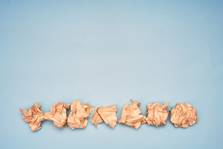 Lump crumpled paper on blue background. Eco friendly concept. Copy space. Flat lay.の写真素材
