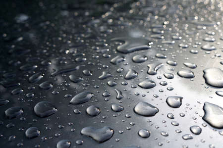 Water drops collect on top of metallic car surface