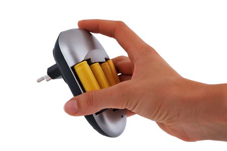 Charger with yellow batteries in hand on a white backgroundの写真素材