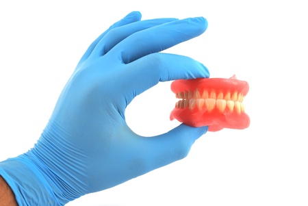 dentures in his hand on a white backgroundの写真素材
