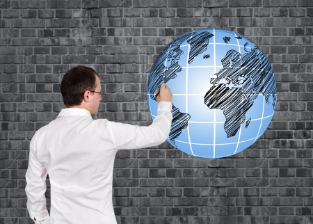 businessman drawing globe on brick wallの写真素材