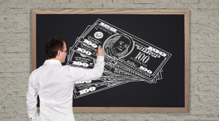 young businessman drawing dollars on  blackboardの写真素材