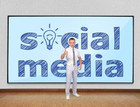 Young businessman showing thumb up and screen with social mediaの写真素材