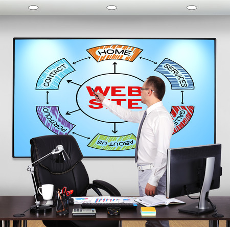 businessman in office pointing to scheme websiteの写真素材