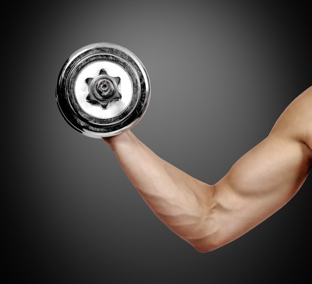 muscular hand holding dumbbell on a black backgroundの写真素材