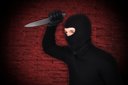 man in mask with knife on red の写真素材