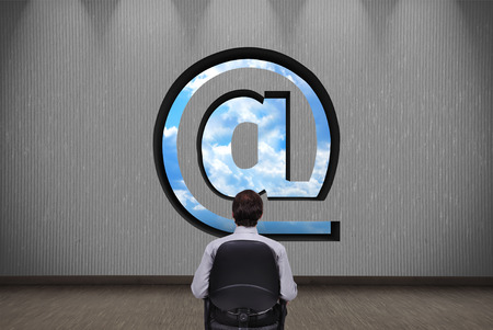 businessman looking on hole in the wall in form of emailの写真素材
