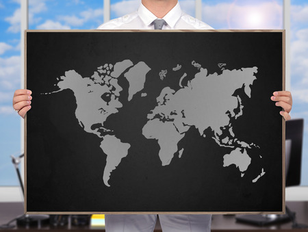 businessman holding blackboard with drawing world mapの写真素材
