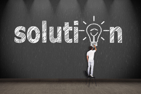 businessman standing on chair and drawing solutionの写真素材