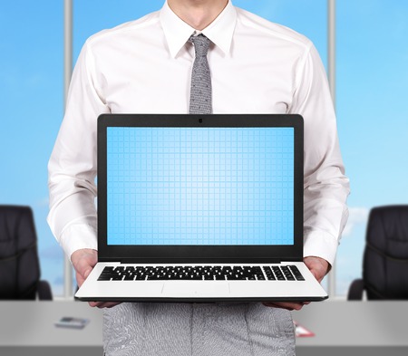 young businessman holding laptop with blank screenの写真素材