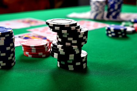 black stacks of poker chips on green table