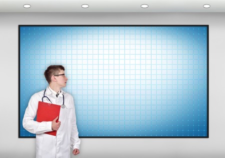 doctor with clipboard looking to blank screenの写真素材