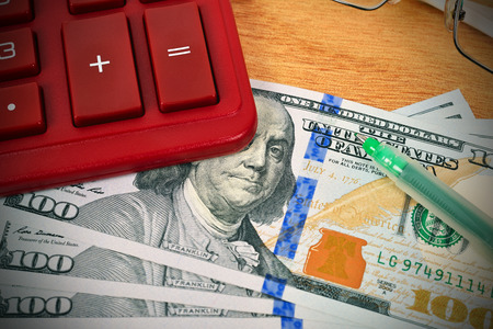 Stack of dollar bills with a calculator and penの写真素材