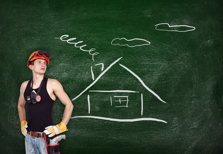 repairman with drill and drawing house on blackboardの写真素材
