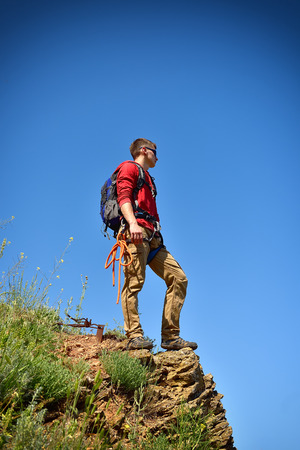young tourist on top of rock on a blue sky backgroundの写真素材