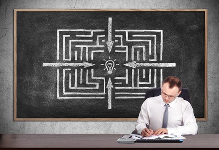 businessman signs a contract and blackboard with drawing labyrinthの写真素材